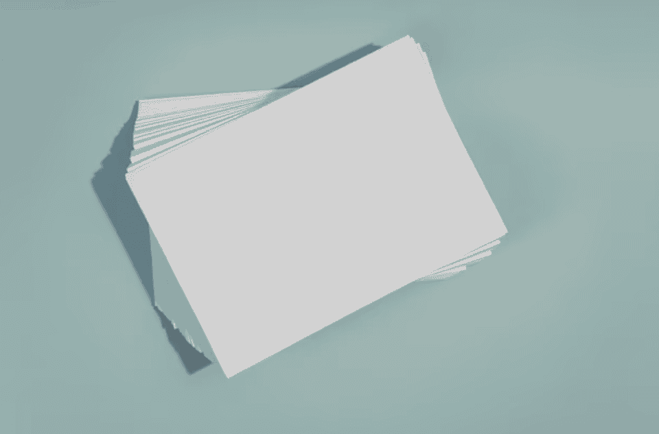 Guia Completo dos Tipos de Papel para Impressão 10 Pilha de folhas de papel branco sobre uma superfície clara