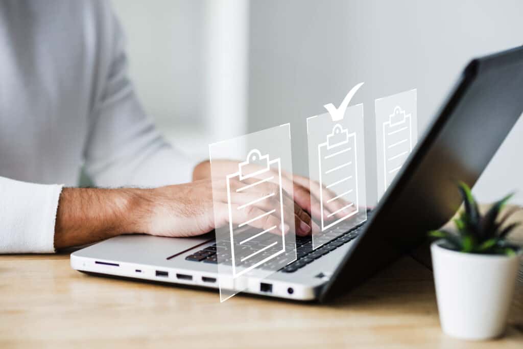 7 melhores práticas na gestão de documentos empresariais 8 Pessoa digitando em um notebook com ícones de checklist e documentos digitais sobrepostos