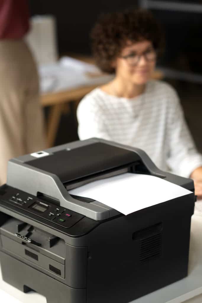 Como evitar travamento de papel 1 Mulher trabalhando ao lado de uma impressora multifuncional a laser em um escritório