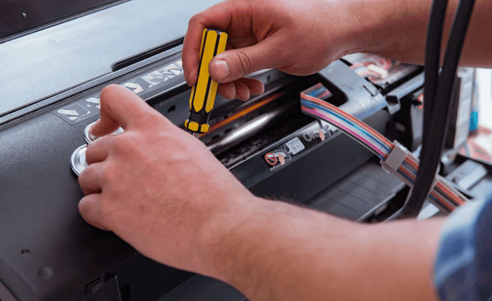 Técnico realizando manutenção no interior de uma impressora com uma chave de fenda