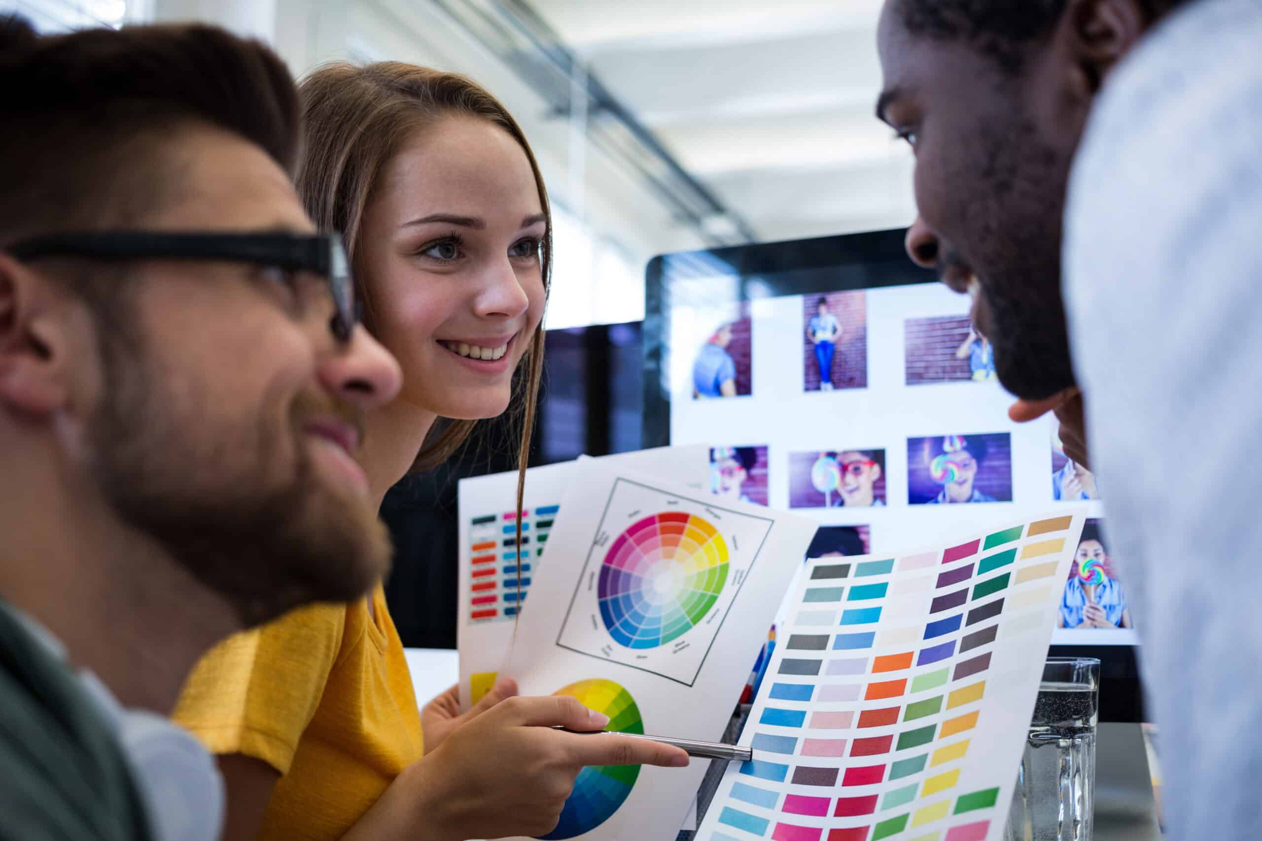 Designers gr&aacute;ficos analisando uma cartela de cores em um escrit&oacute;rio