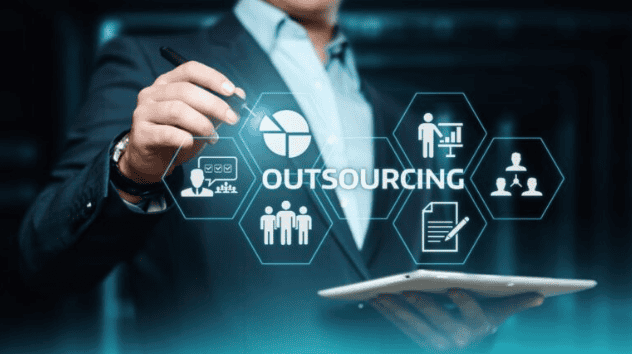 Profissional tocando a palavra outsourcing rodeada de &iacute;cones de servi&ccedil;os