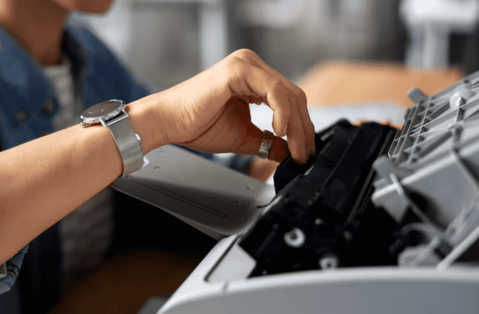 Pessoa instalando o cartucho de toner em uma impressora aberta