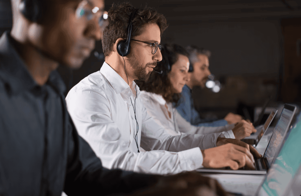 Equipe de atendimento com fones de ouvido trabalhando em laptops em um escritório