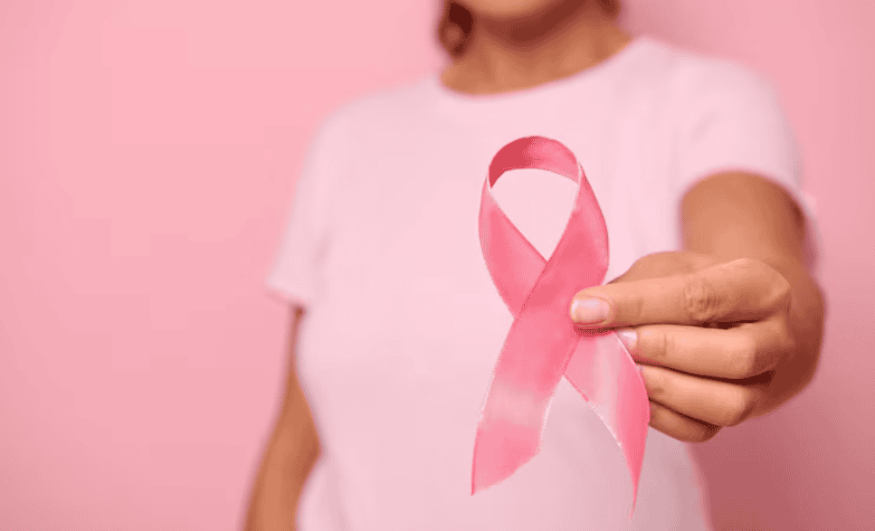 Pessoa segurando um laço rosa de conscientização sobre o câncer de mama