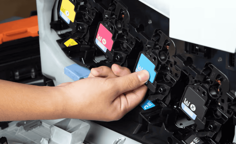 M&atilde;o inserindo cartuchos de tinta coloridos em uma impressora jato de tinta