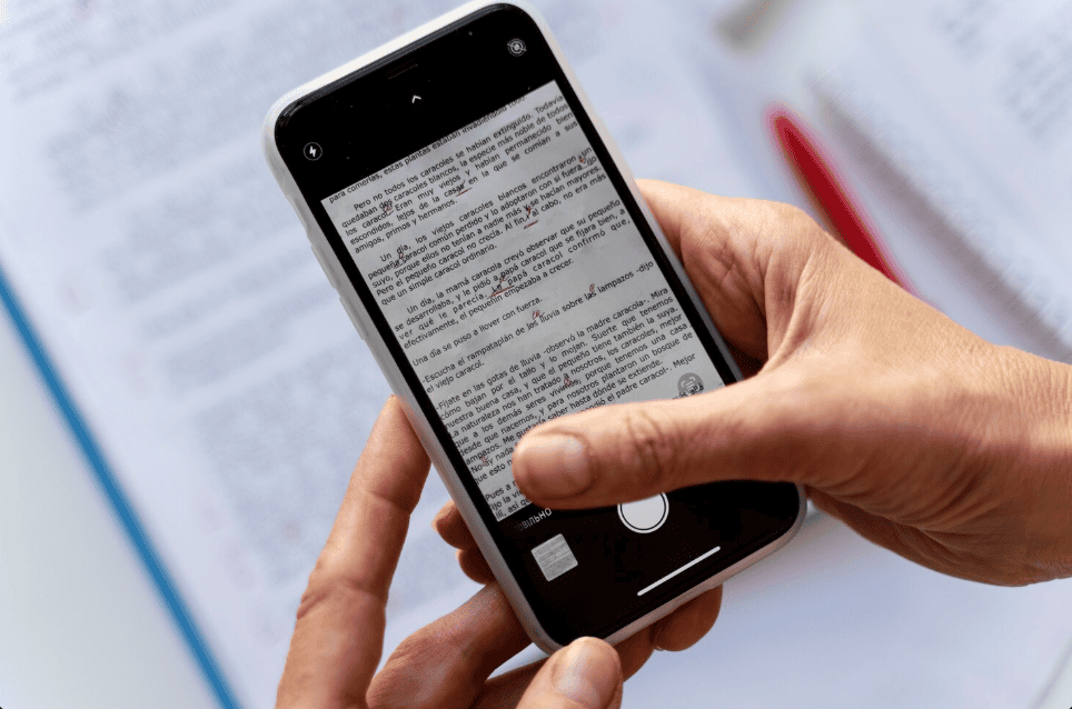 Mãos usando um smartphone para escanear um documento impresso