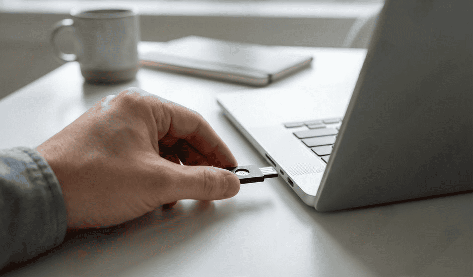 Mão conectando um pen drive na porta USB de um notebook
